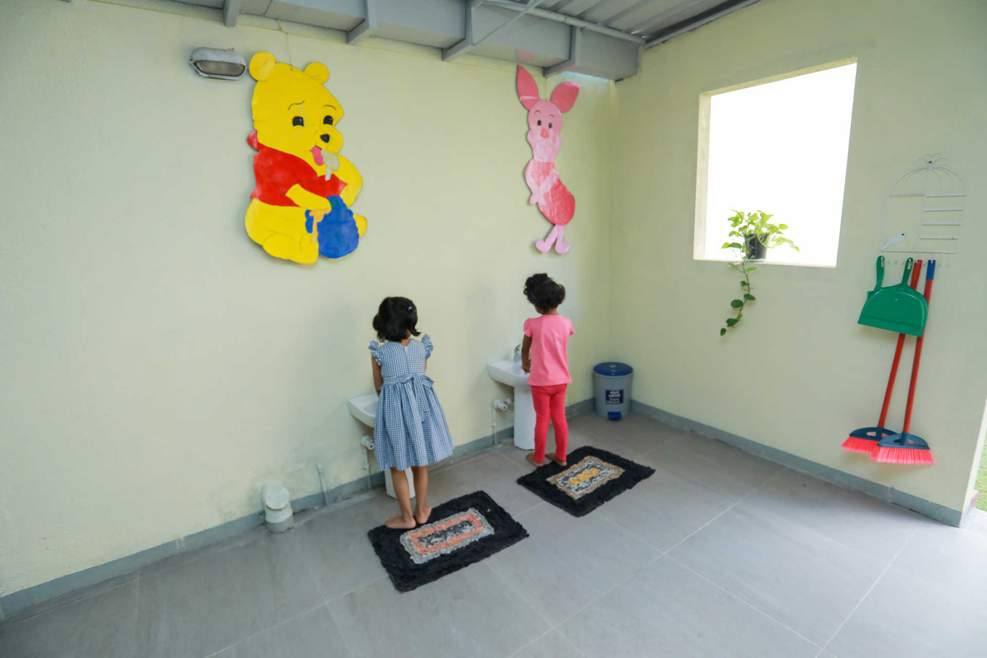 Child-friendly restroom with kids washing hands and Winnie the Pooh decor.