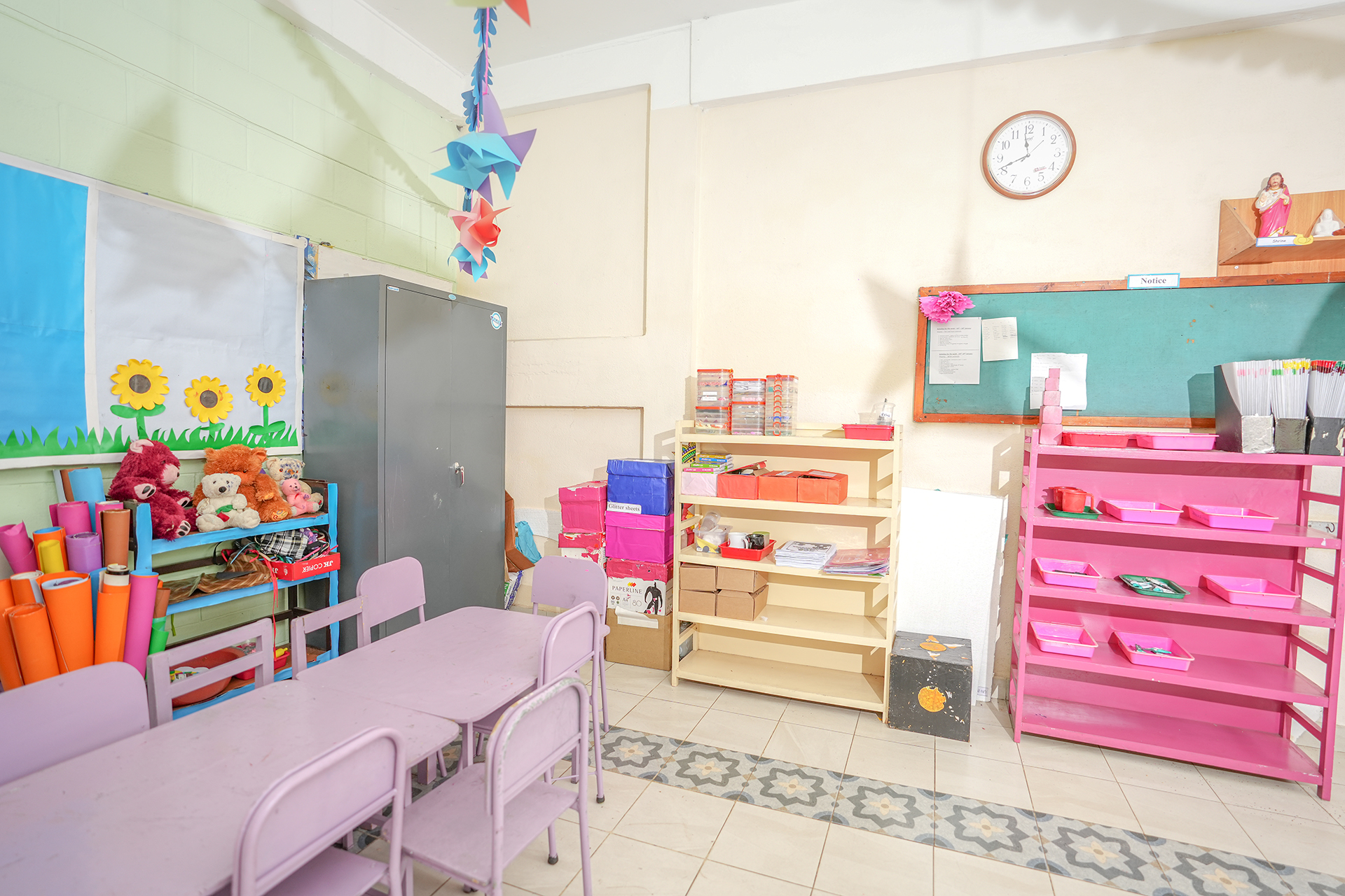 Bright preschool classroom with pastel furniture, shelves of toys, and colorful wall decorations.