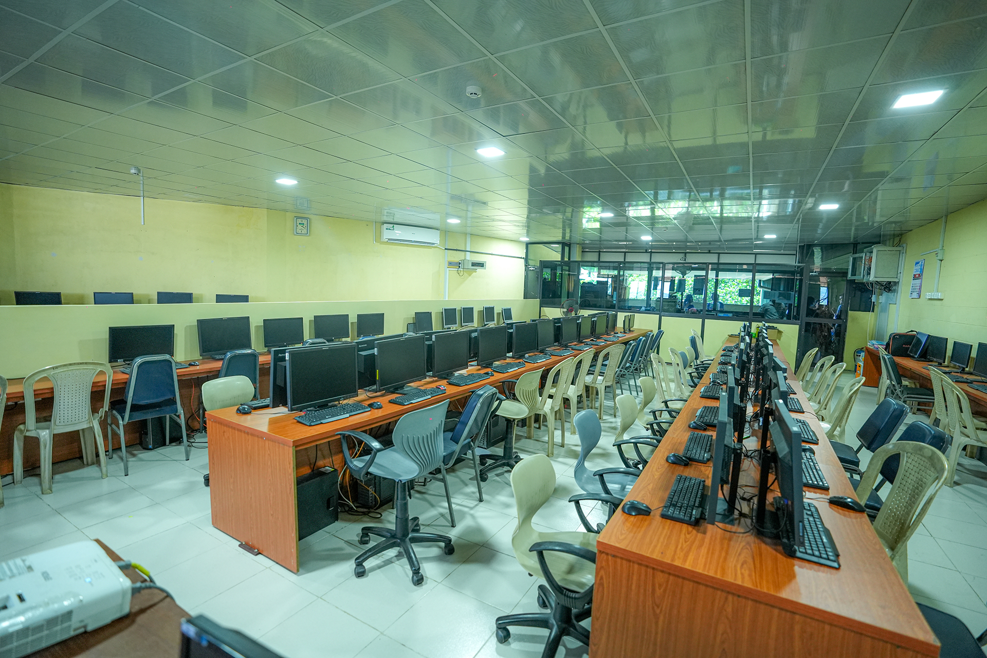 Spacious computer lab with desks, monitors, mixed seating, bright lighting, and large windows.