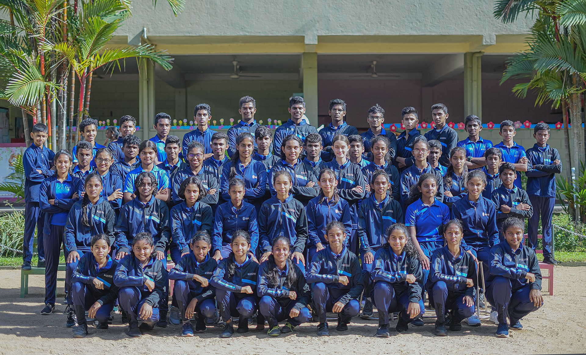 Group of students in blue uniforms posing outdoors for a formal photo.