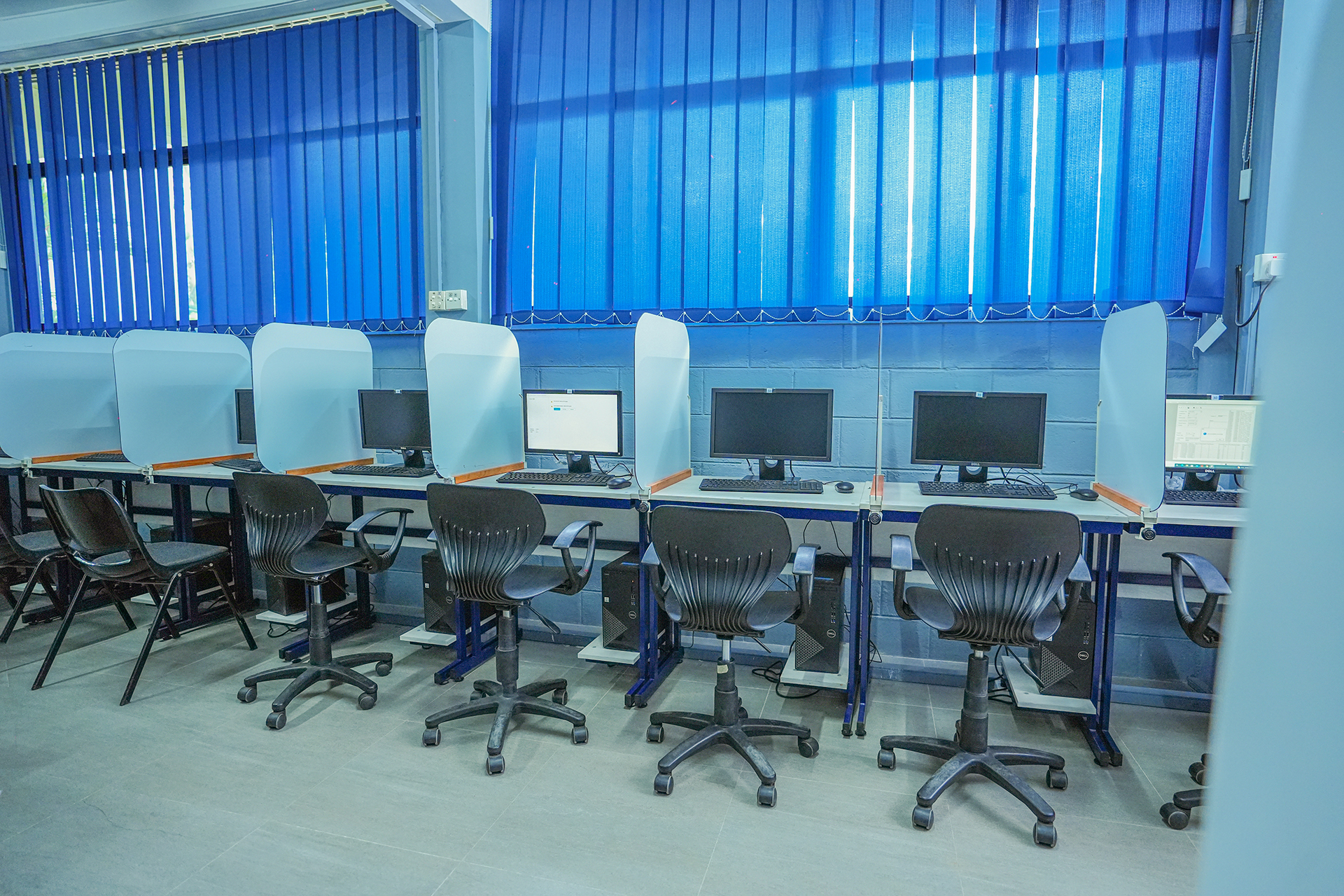 Modern computer lab with ergonomic chairs, individual workstations, and translucent partitions for privacy.