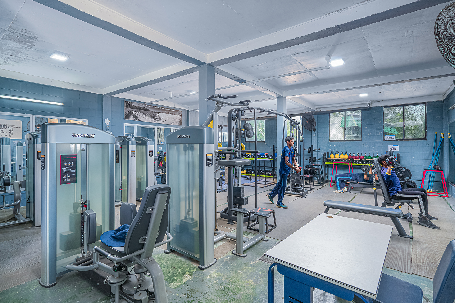 Modern gym with advanced equipment, natural light, and people working out.