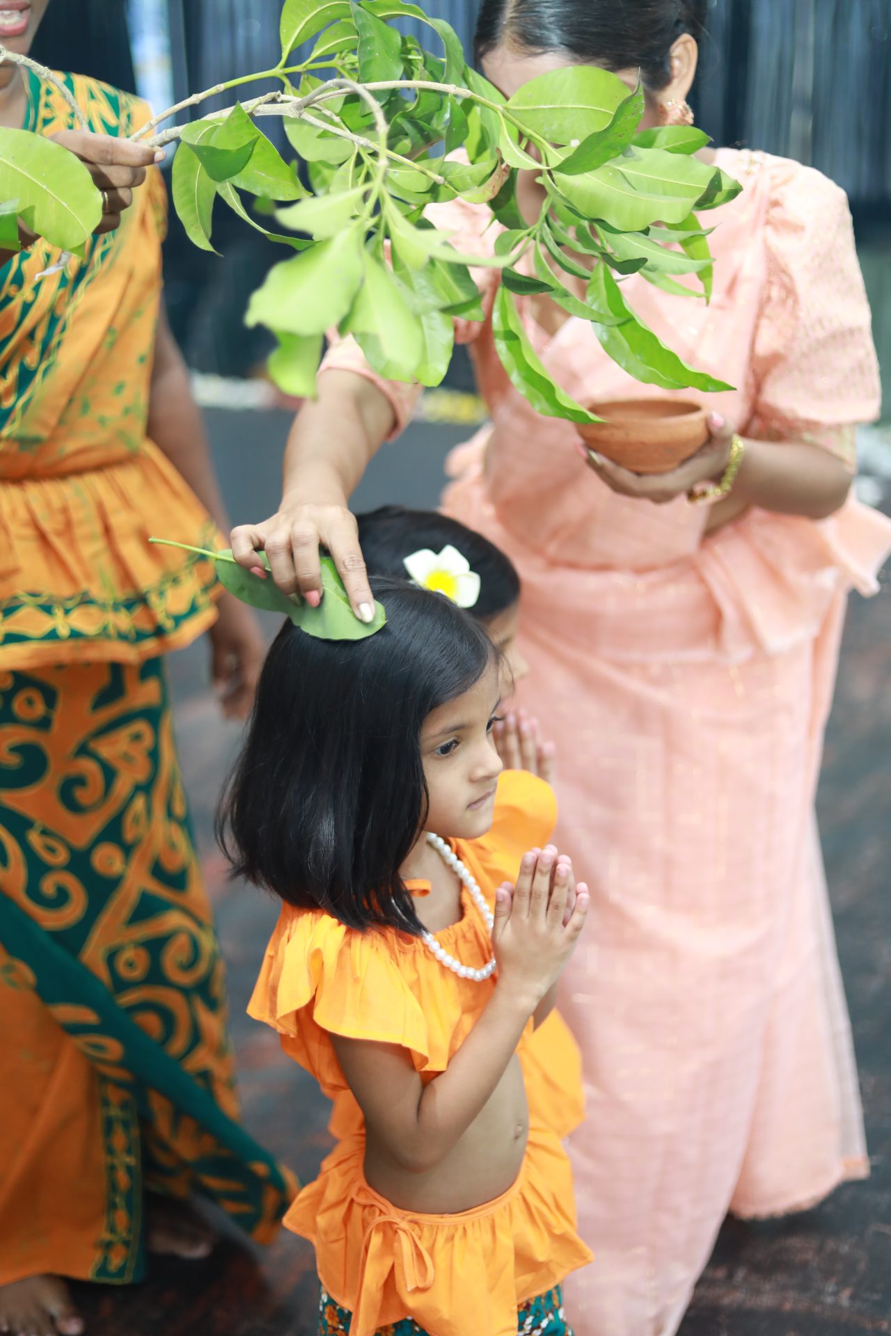 Young girl in traditional attire receiving blessing from women during cultural ceremony.