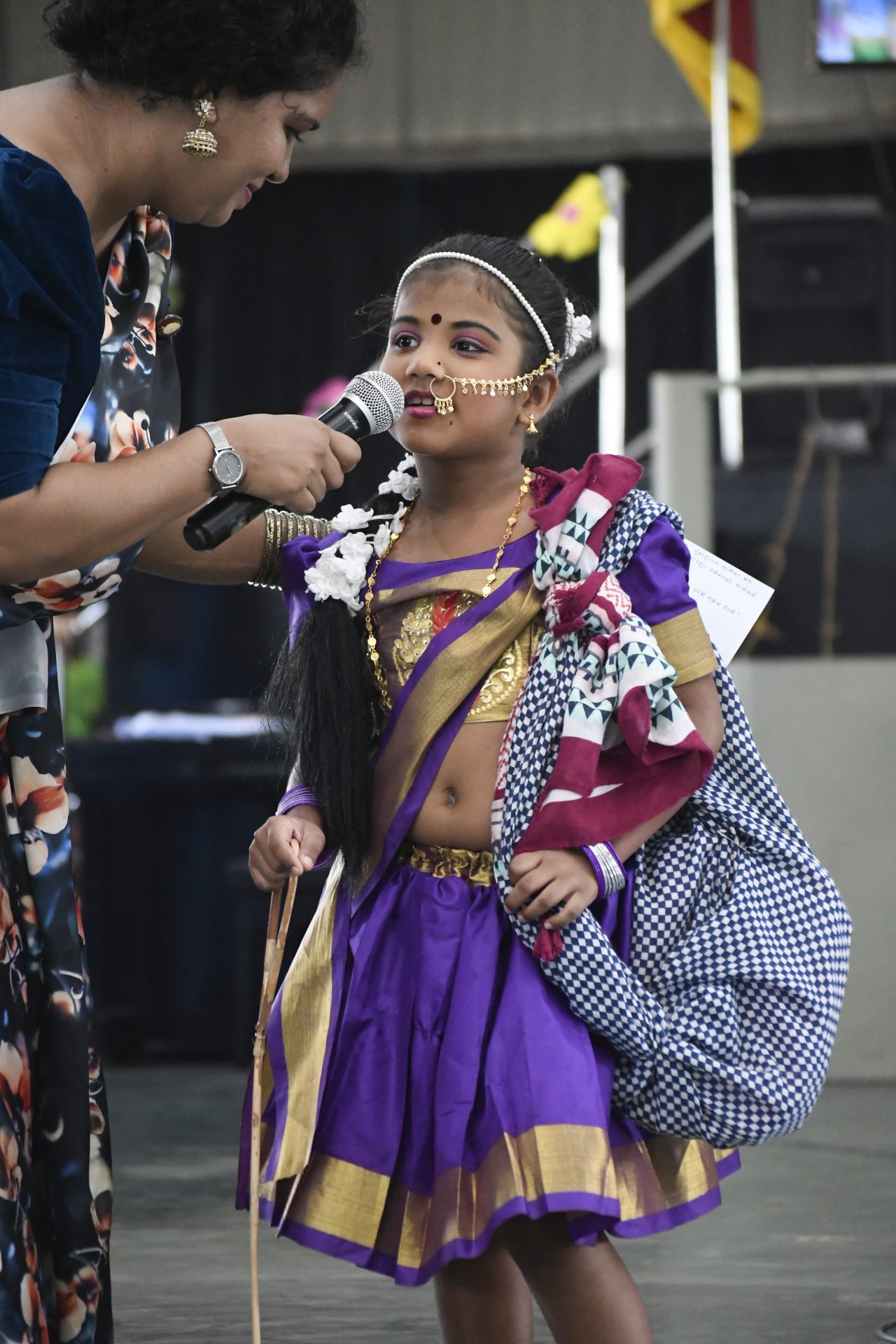 Young girl in traditional attire performing on stage at a cultural event.