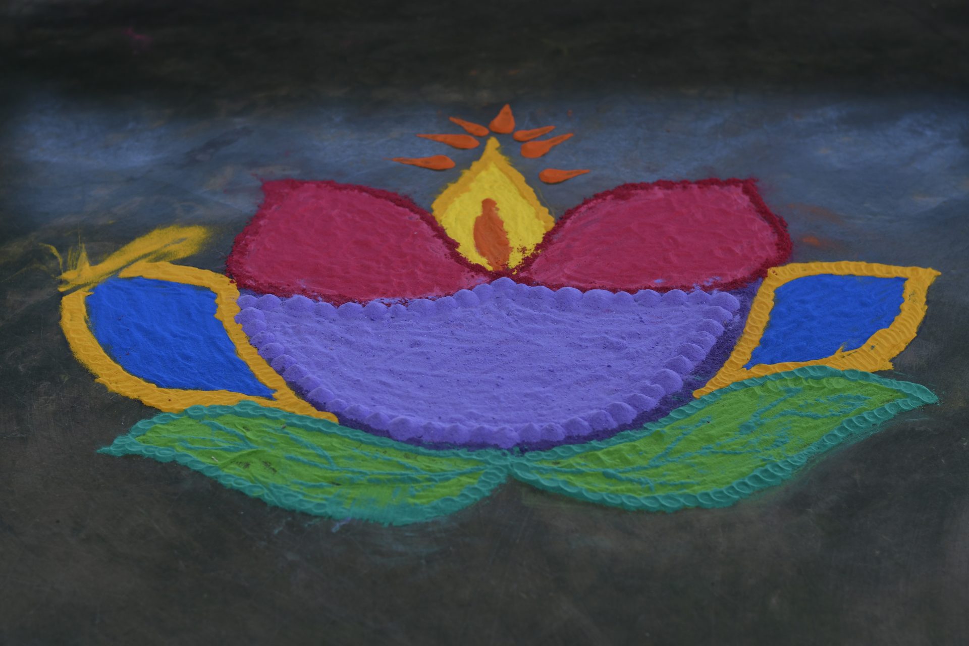 Vibrant lotus rangoli with central diya, colorful petals, and intricate green leaves.