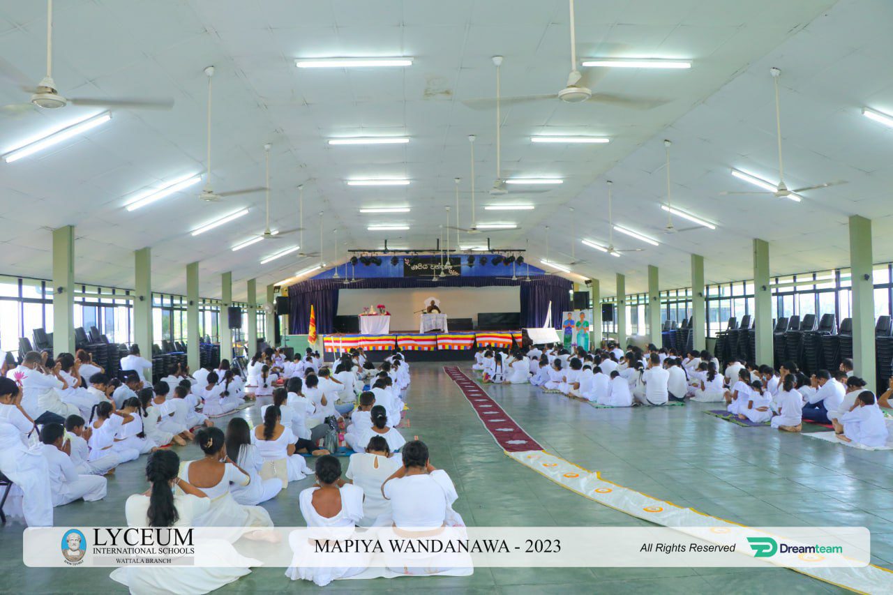 Large hall with people in white seated on the floor for the MAPIYA WANDANAWA 2023 ceremony.