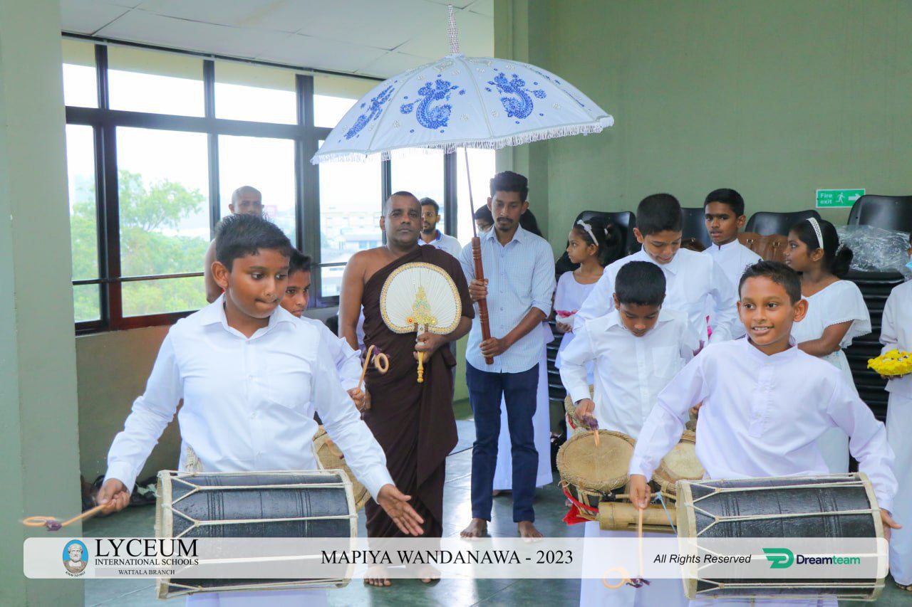 Children playing drums, a monk with a fan, and a banner at Lyceum cultural event.