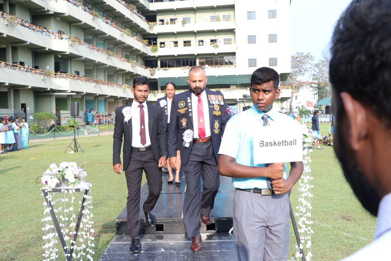 Formal ceremony with officials and a student holding a Basketball sign at an educational institution.