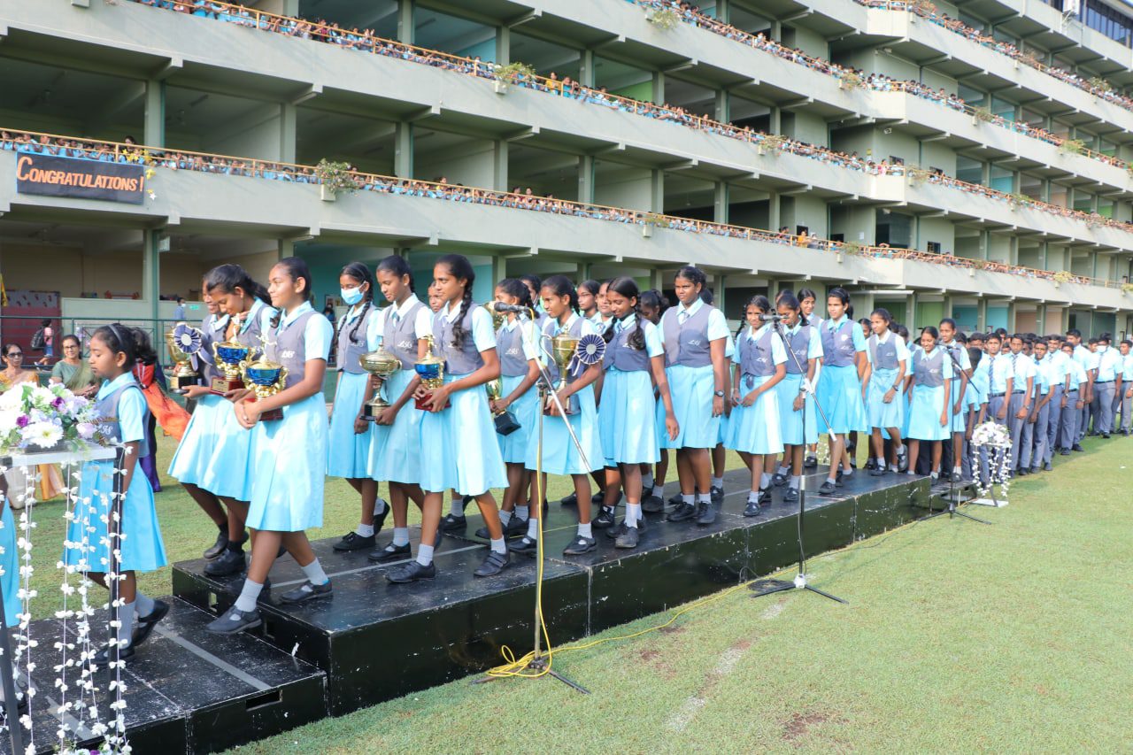 School students holding trophies on a stage during an awards ceremony.