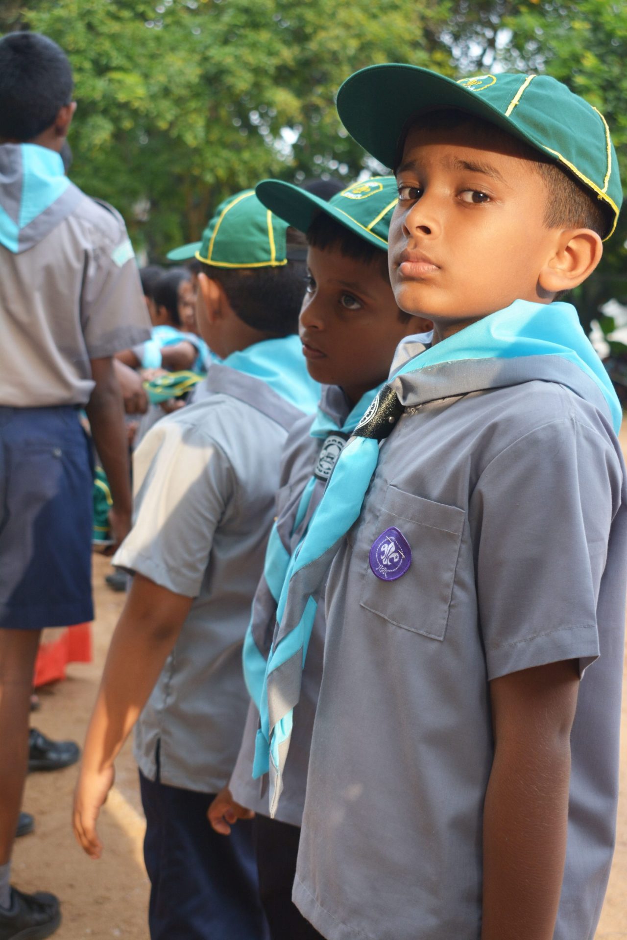 Young scouts in uniform gather outdoors at an event, focused and ready for activities.