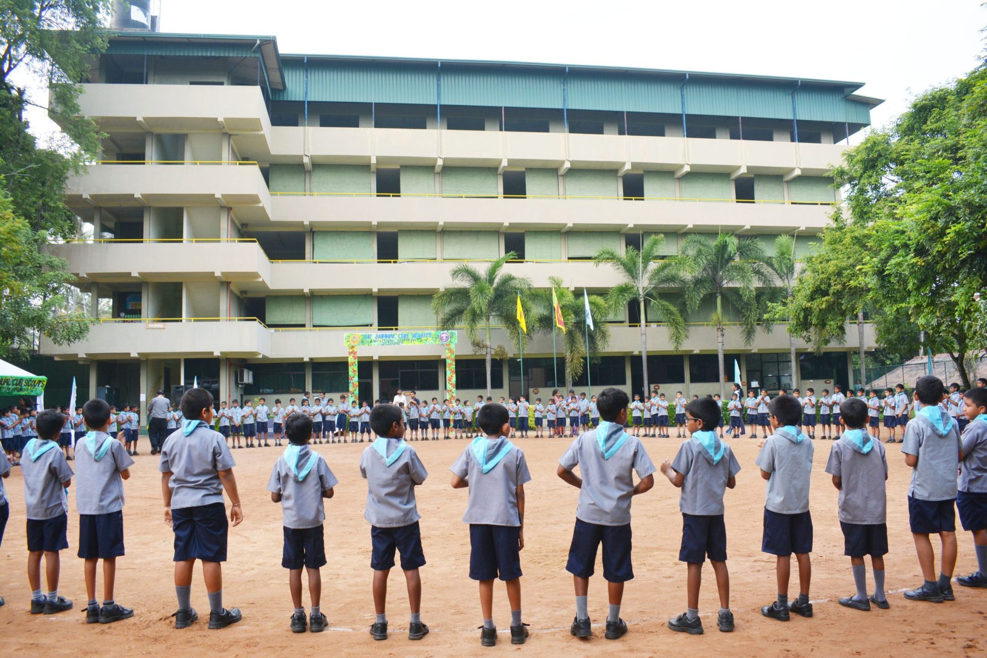 School scouts in uniform gather outside modern building for ceremony.