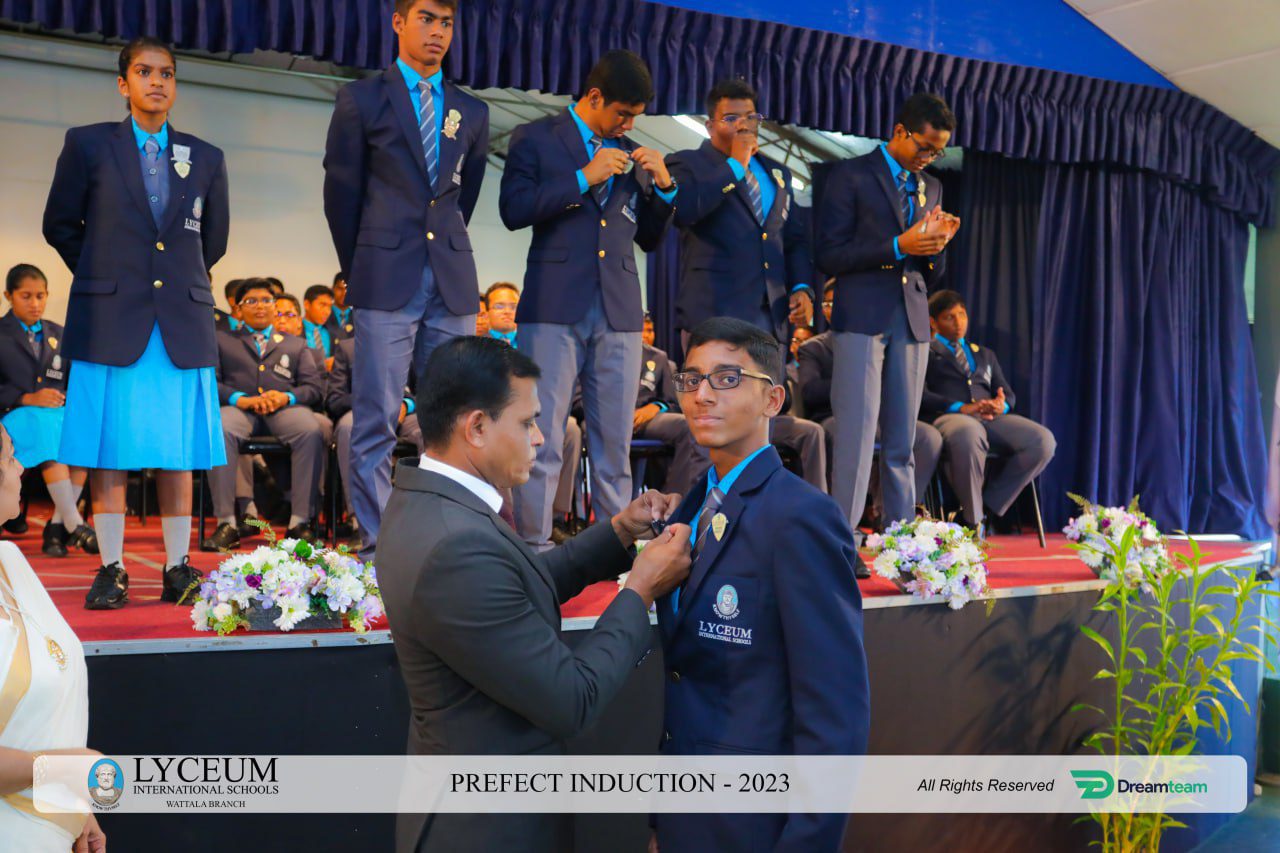 Lyceum 2023 Prefect Induction Ceremony: Students receiving badges on stage.