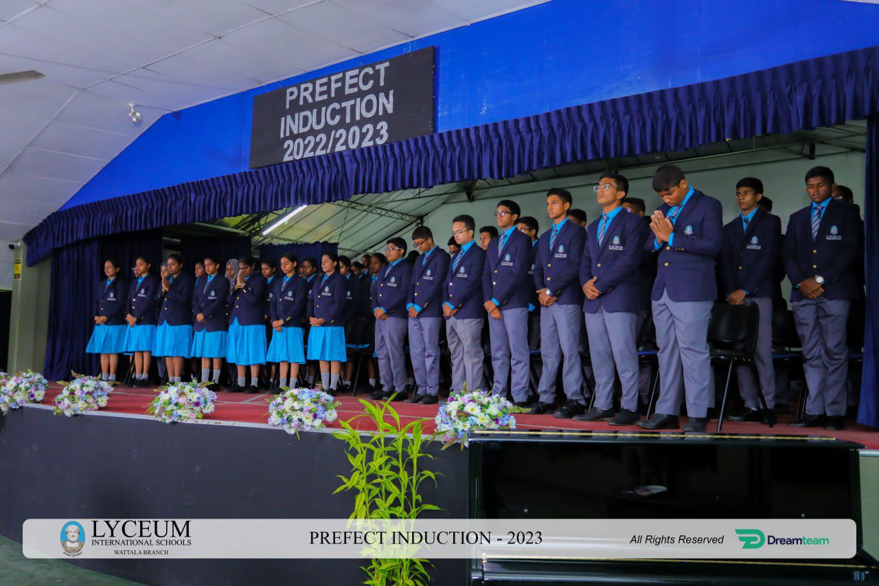Lyceum Prefect Induction 2022/2023 at Wattala branch; students in formal attire on stage.