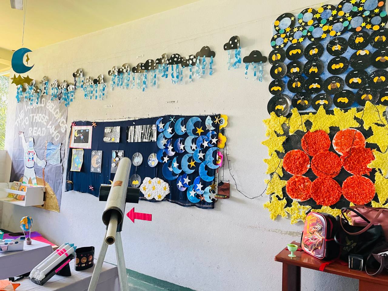 Classroom with celestial decorations, telescope, moon phases, stars, and clouds.