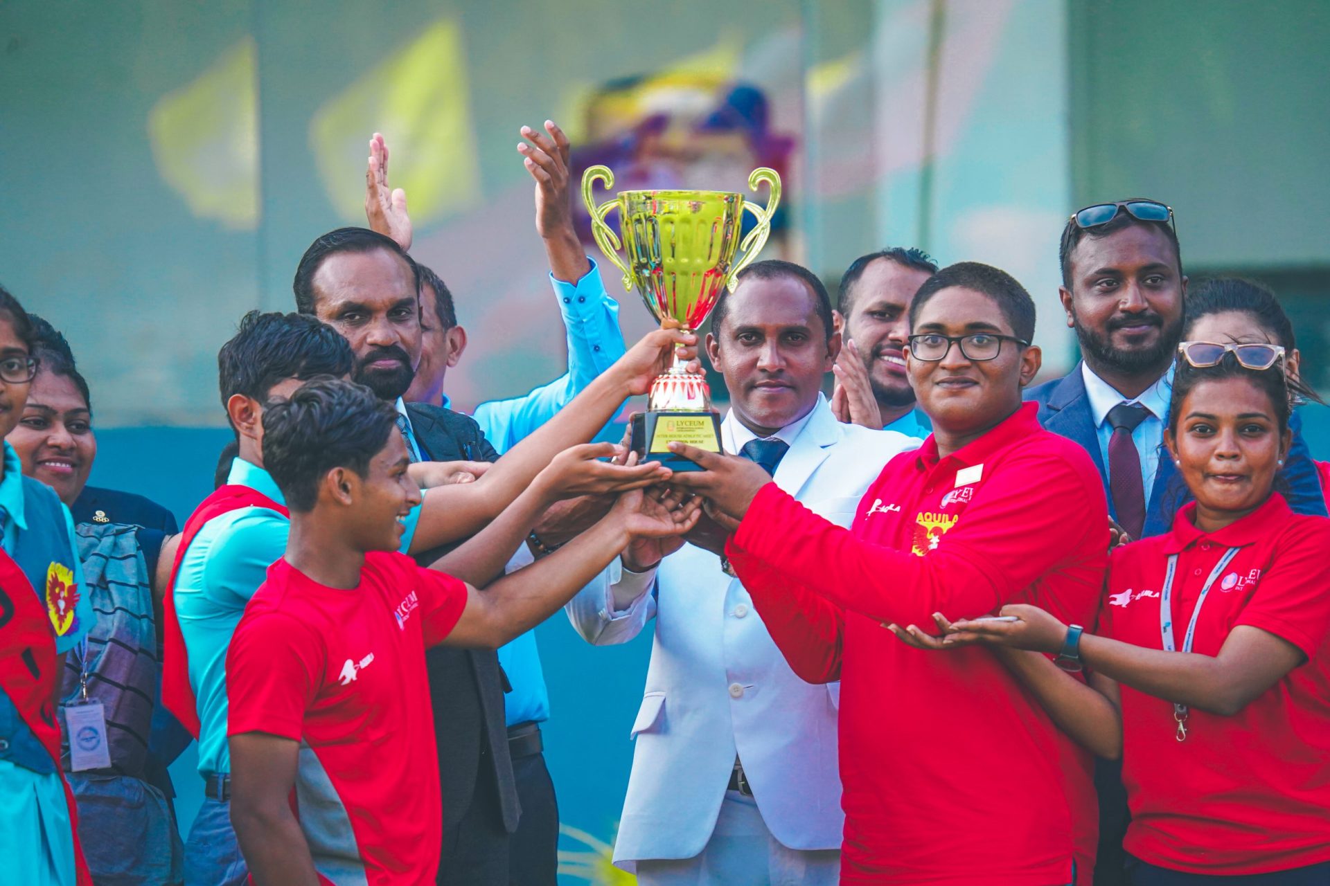 Youth team joyfully celebrates victory with golden trophy.