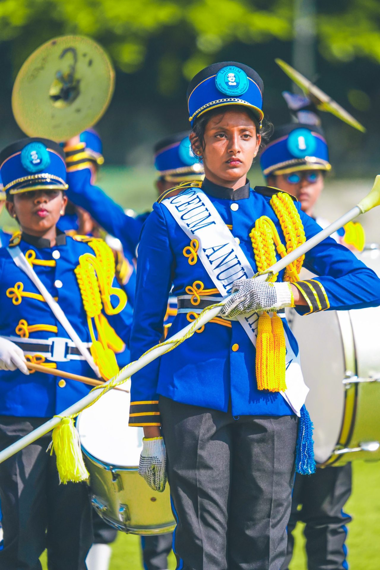 Young marching band in blue and gold uniforms performing outdoors.