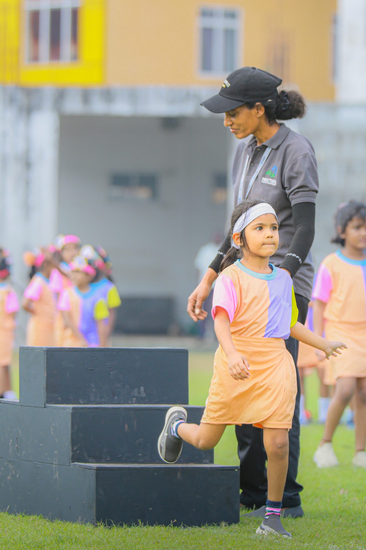 Child athlete at school sports event steps off podium with coachs support.