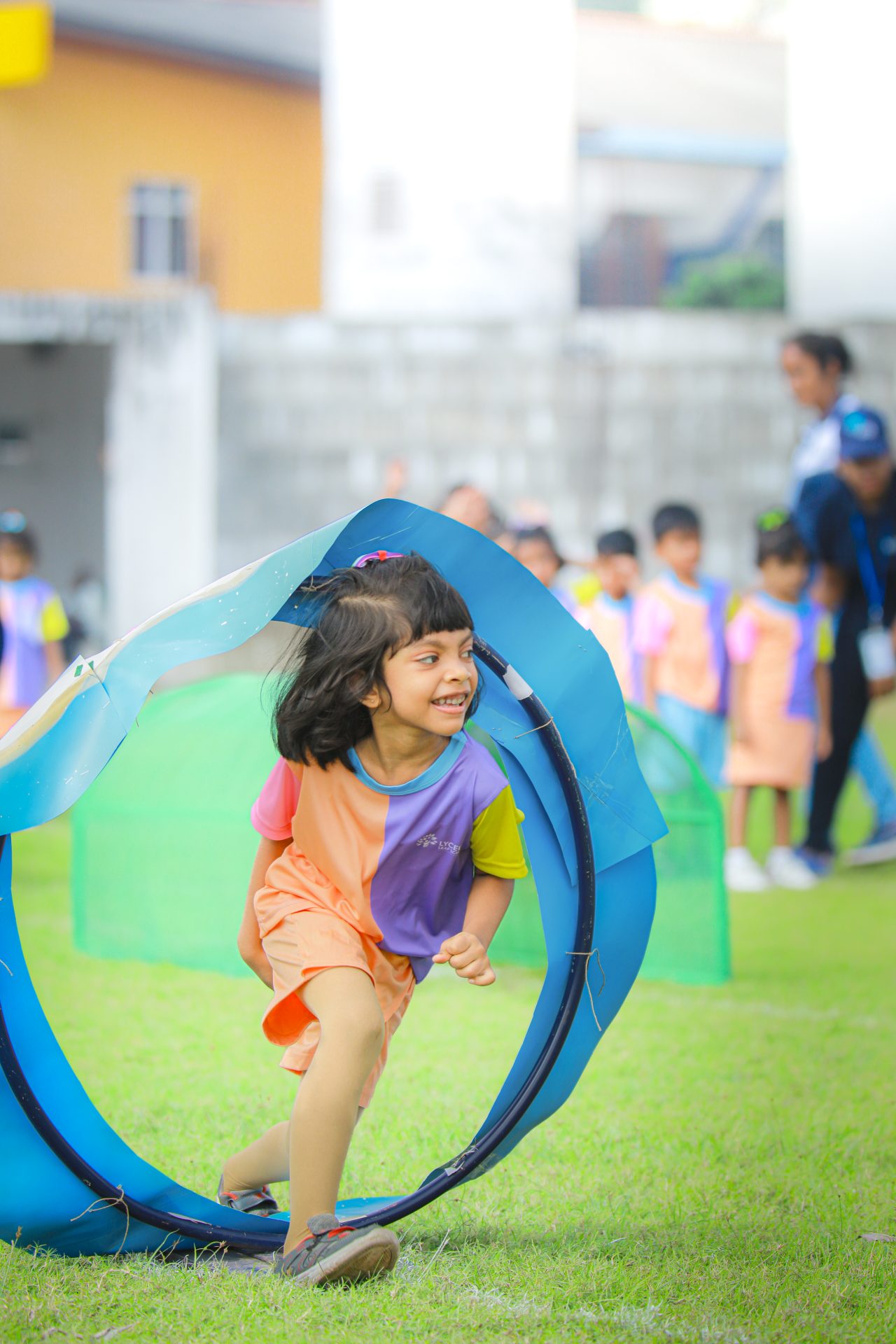 Girl running through a tunnel at kids sports day event.