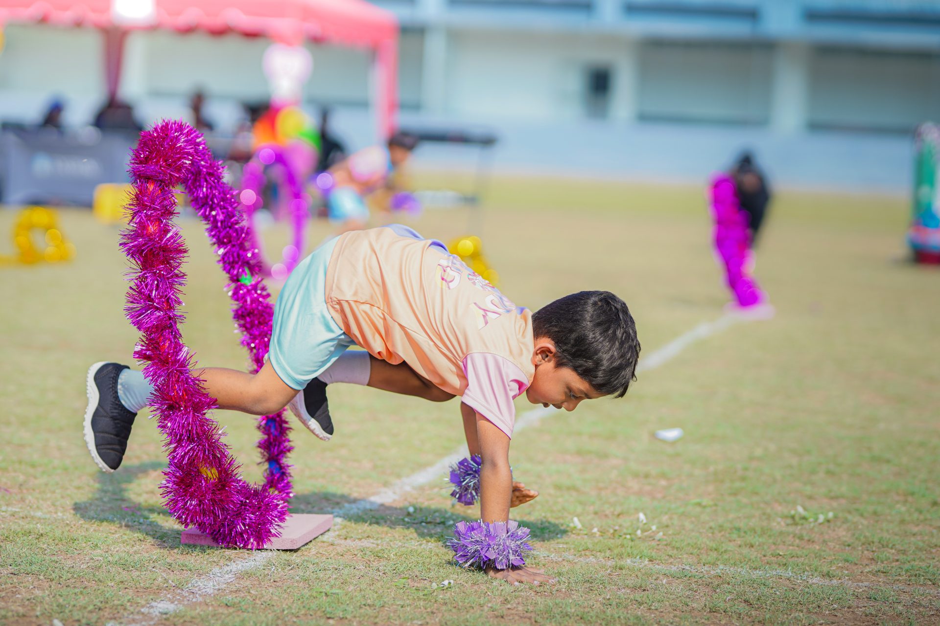 Boy Crawling Through Tinsel Hoop at School Event.
