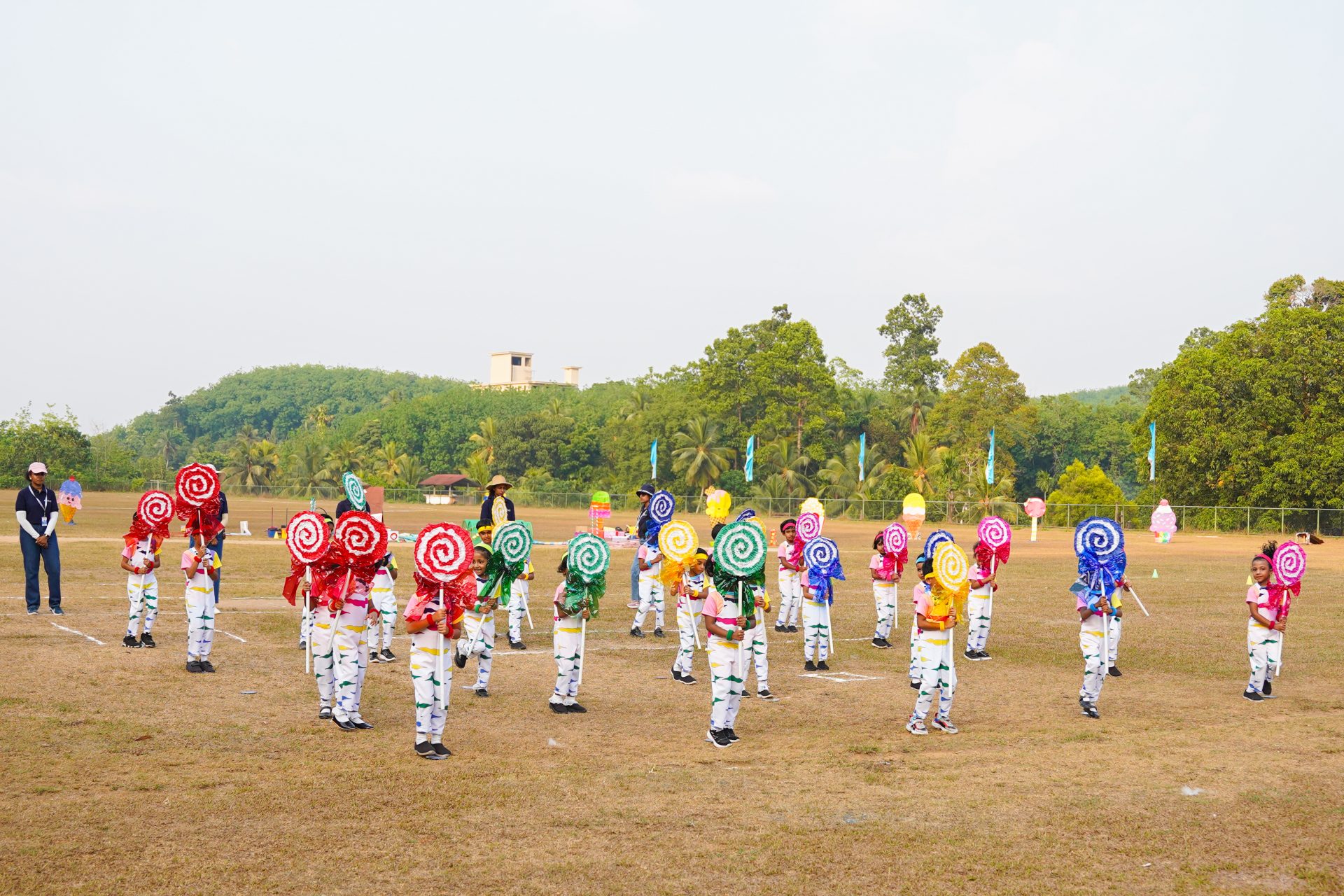 Participants in colorful costumes perform a traditional dance on a grassy field with onlookers.