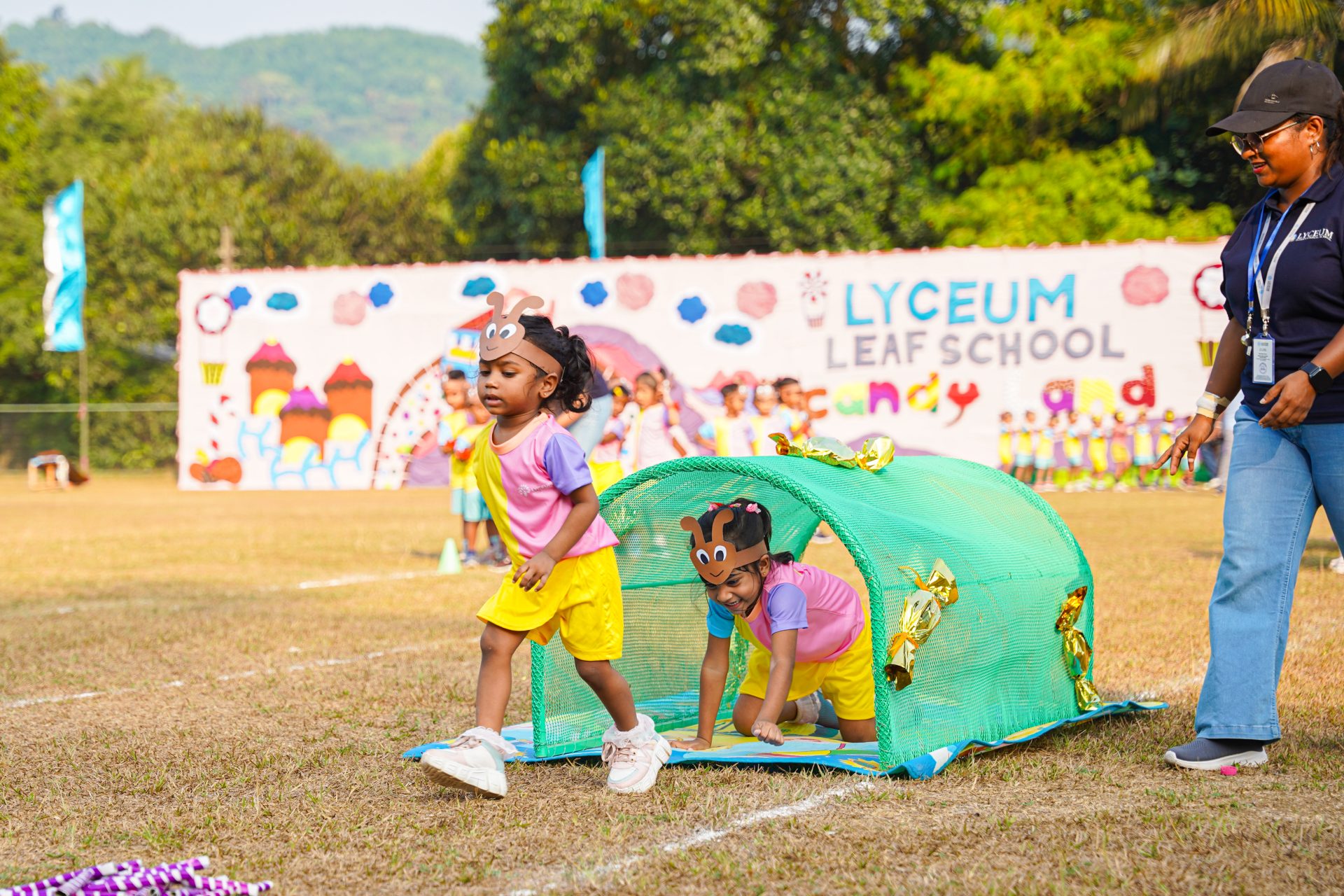 Children in colorful outfits enjoy outdoor school sports day activities.