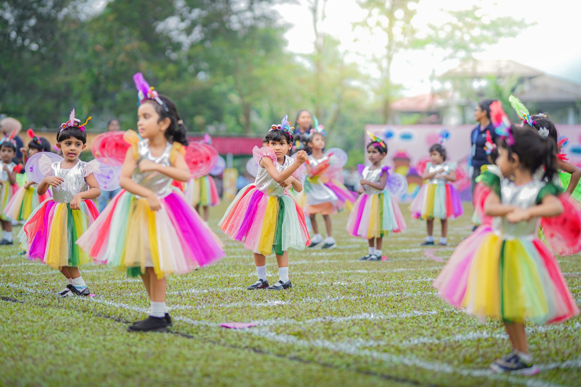 Childrens dance performance in colorful costumes on a grassy field.