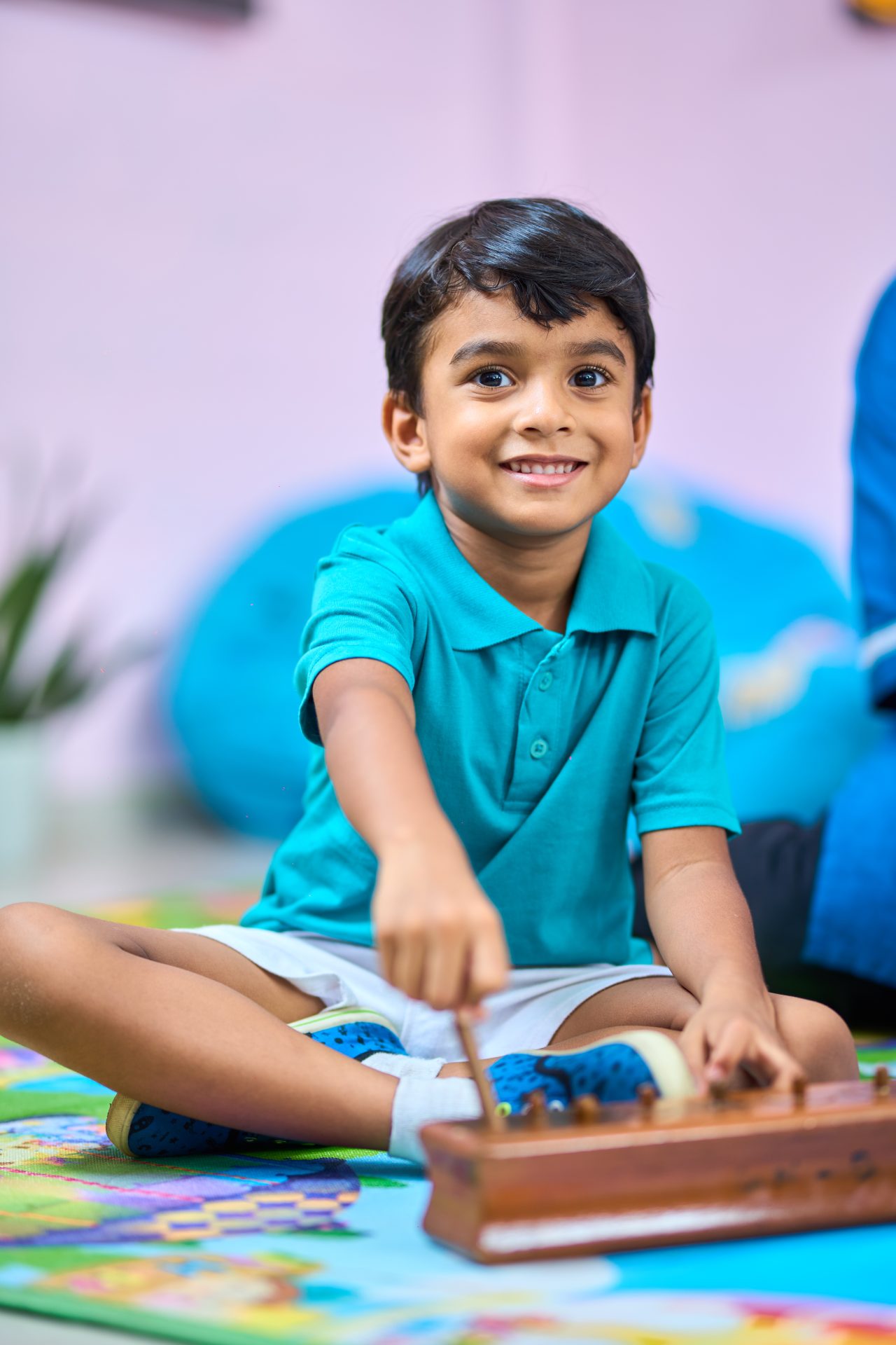 Boy joyfully playing xylophone in colorful, cozy playroom.