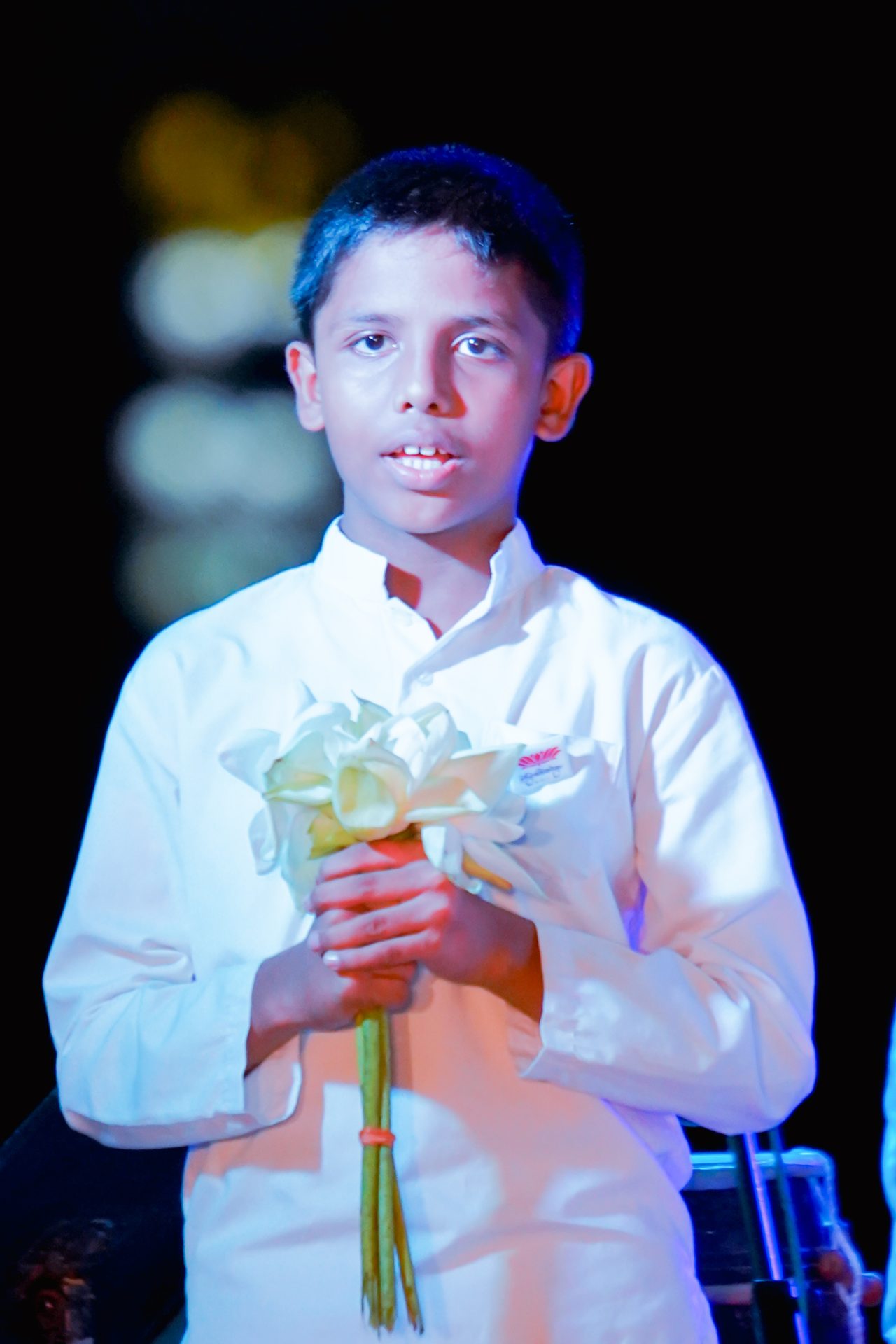 Young boy holding a bouquet of white lilies.