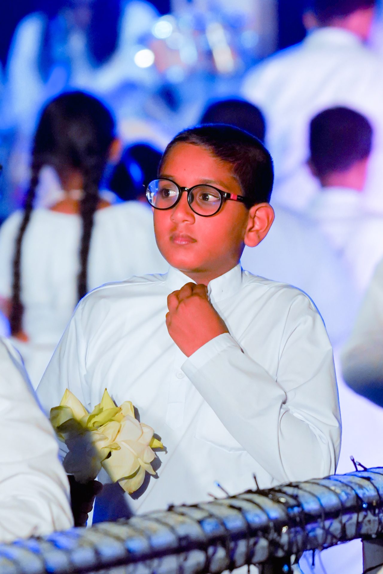 Young boy in formal attire holding flowers at a ceremony.