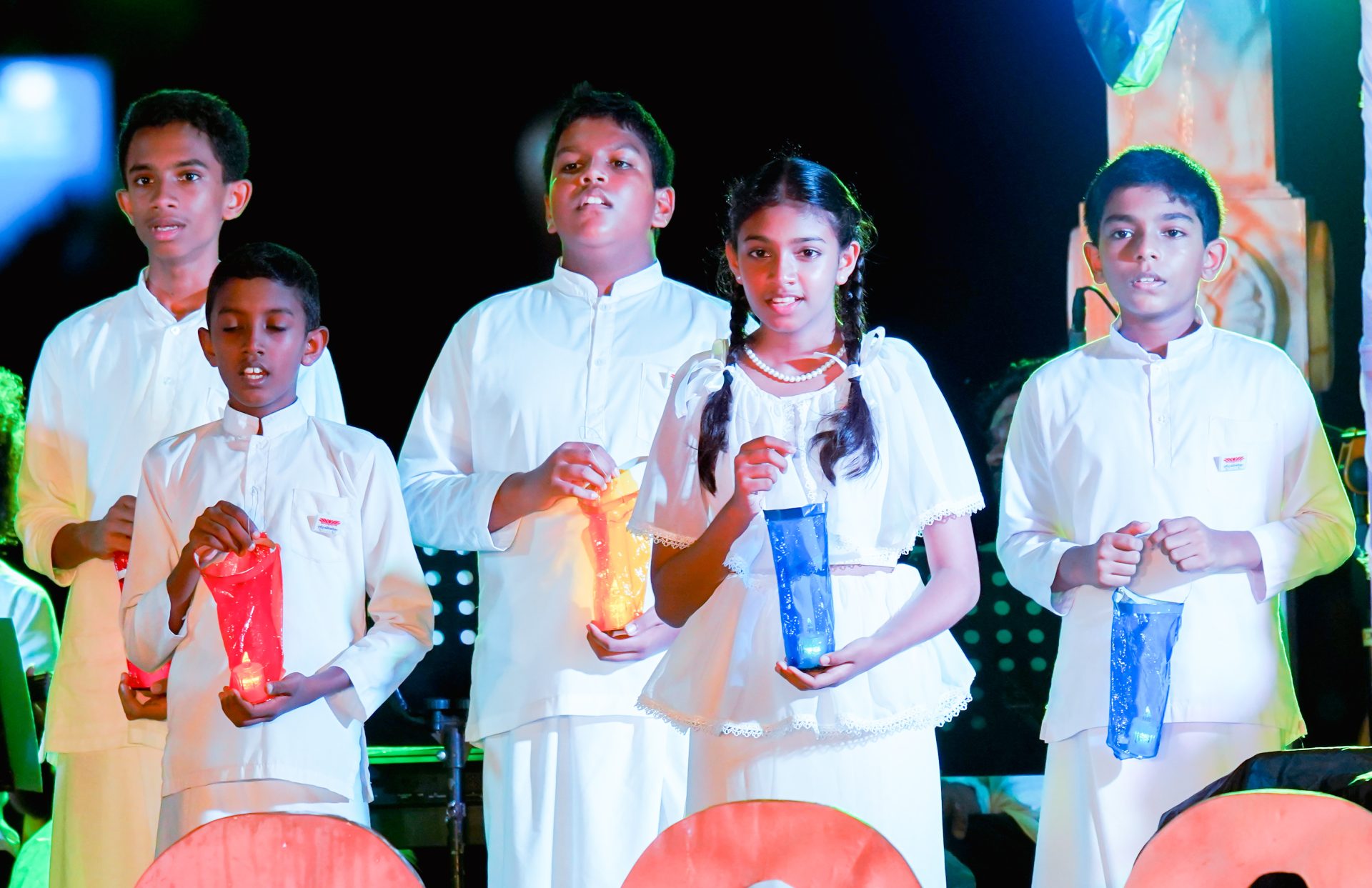 Children holding lanterns in solemn ceremony performance.