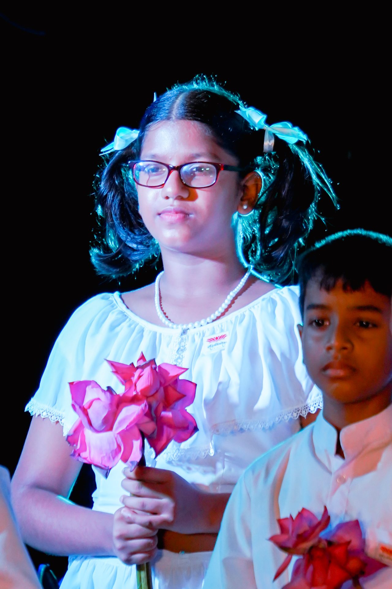 Children at ceremony holding pink lotus flowers.