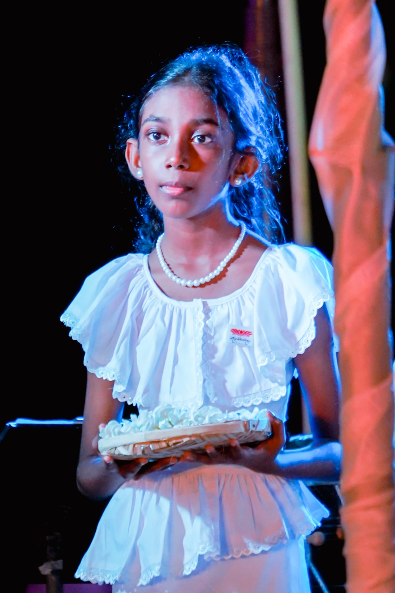 Young girl with flowers in wicker basket at ceremony.