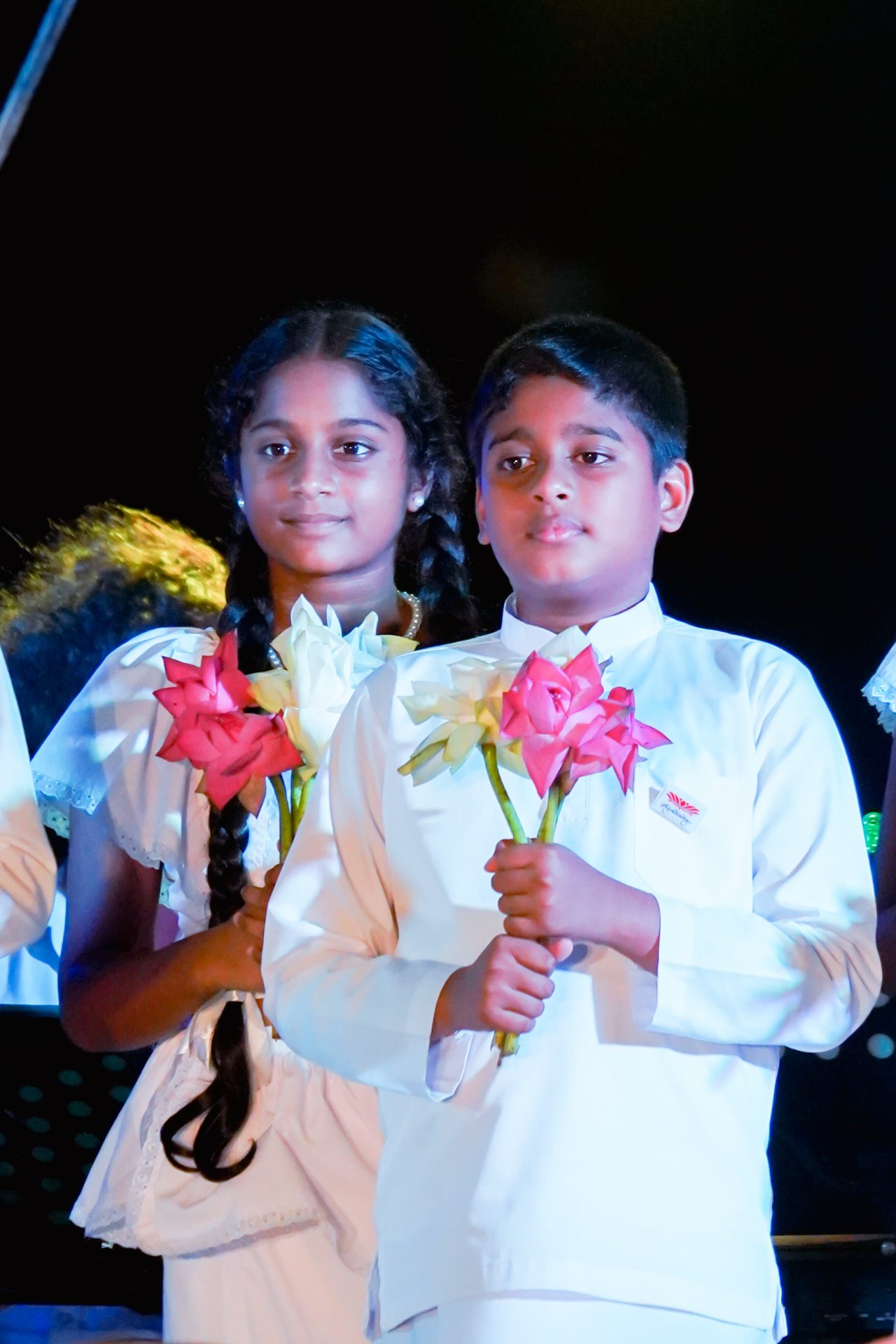 Two children holding flowers in a formal ceremony.