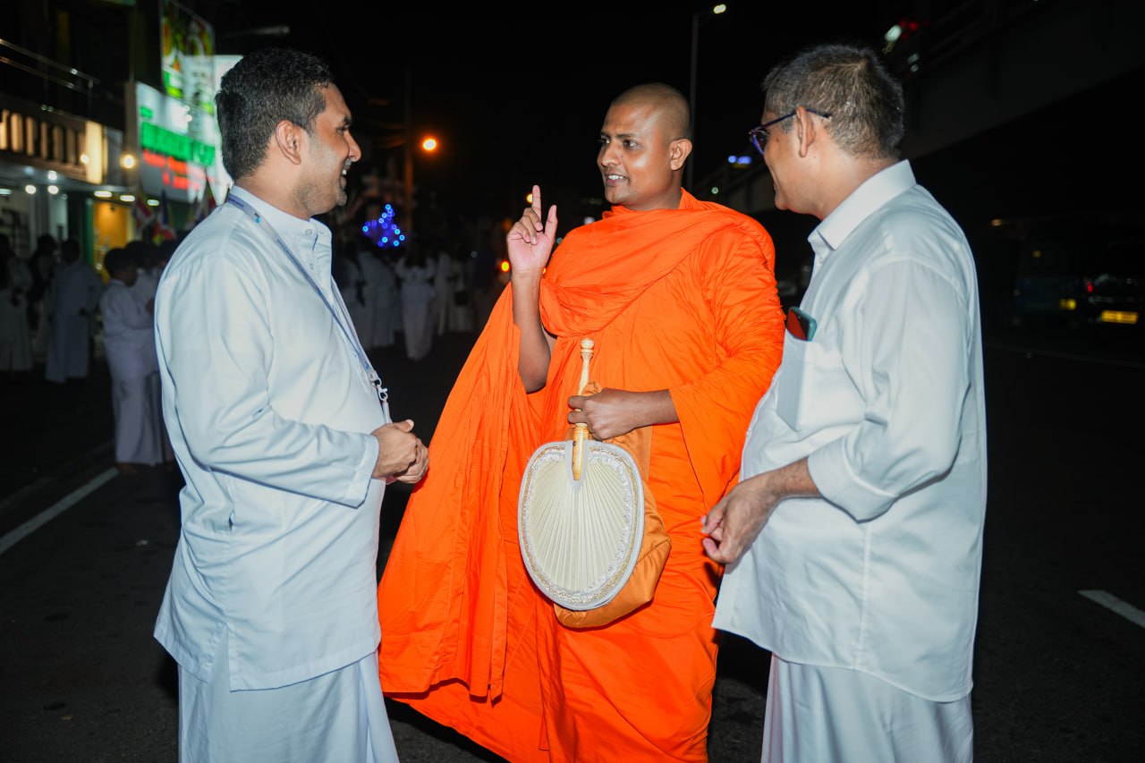 Buddhist monk discussing on a dimly lit street at night with two men.
