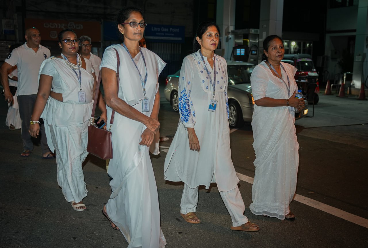 Group in formal white attire walking on urban night street.