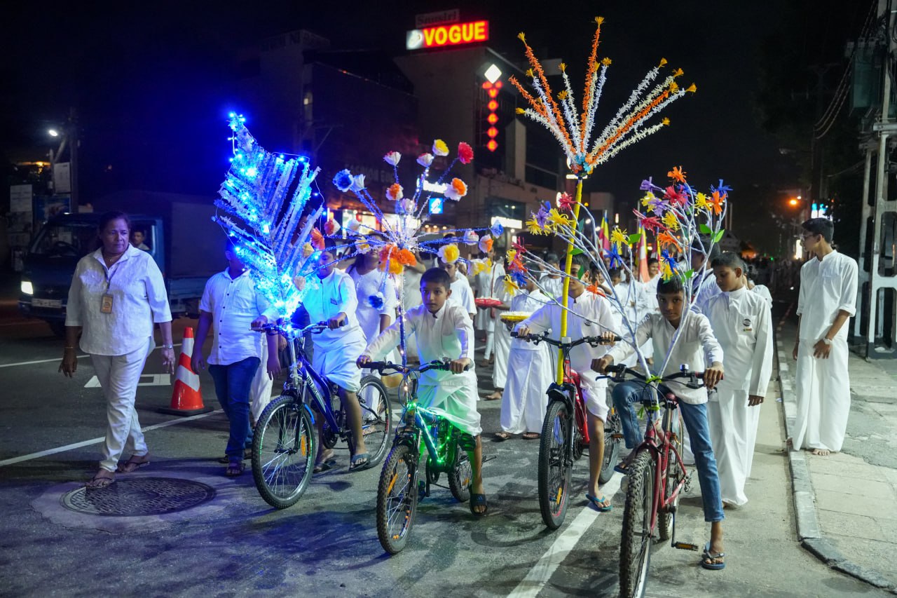 Nighttime parade with illuminated bicycles and participants in white clothing celebrating.
