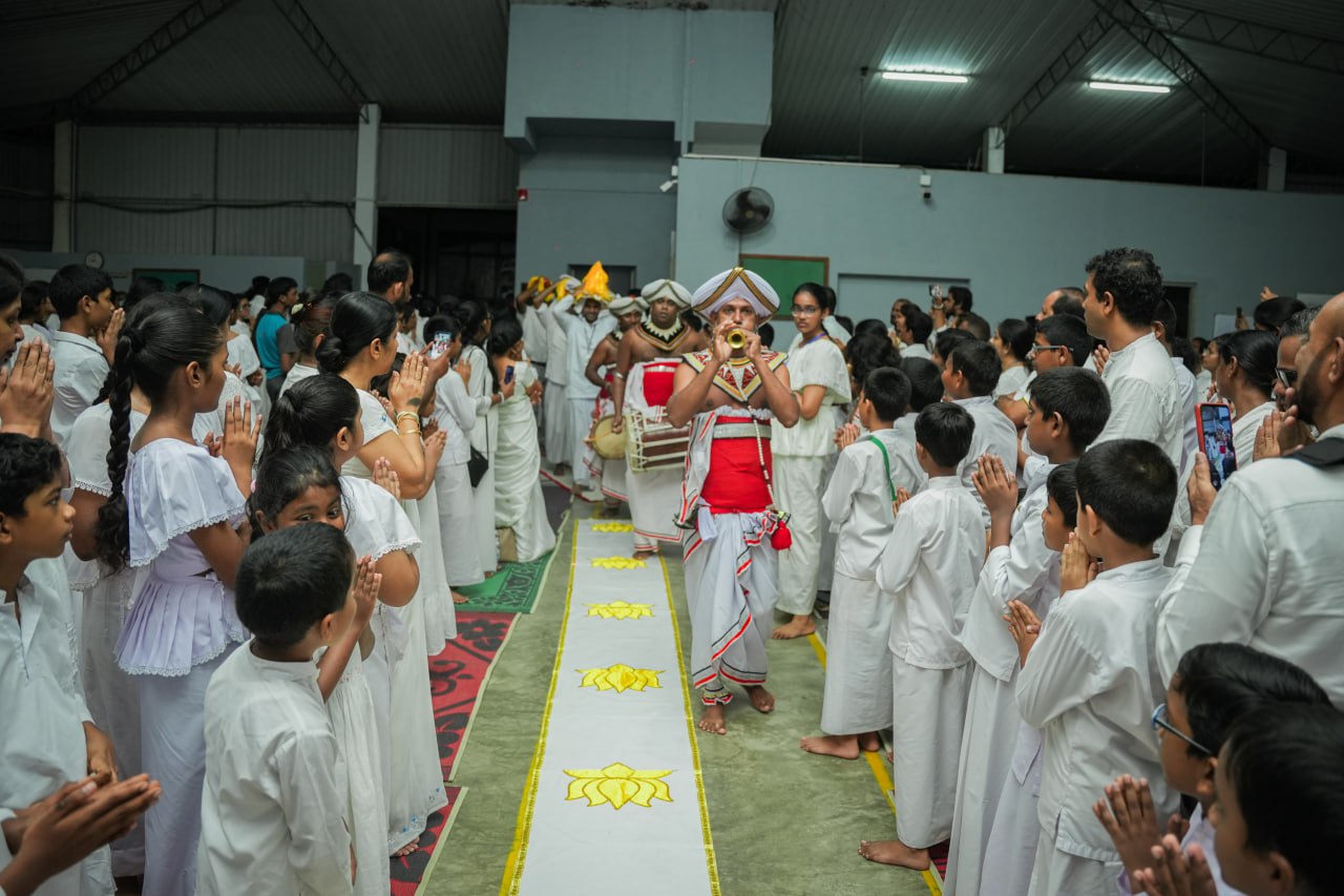 Traditional indoor cultural procession with performers and attendees in white attire.