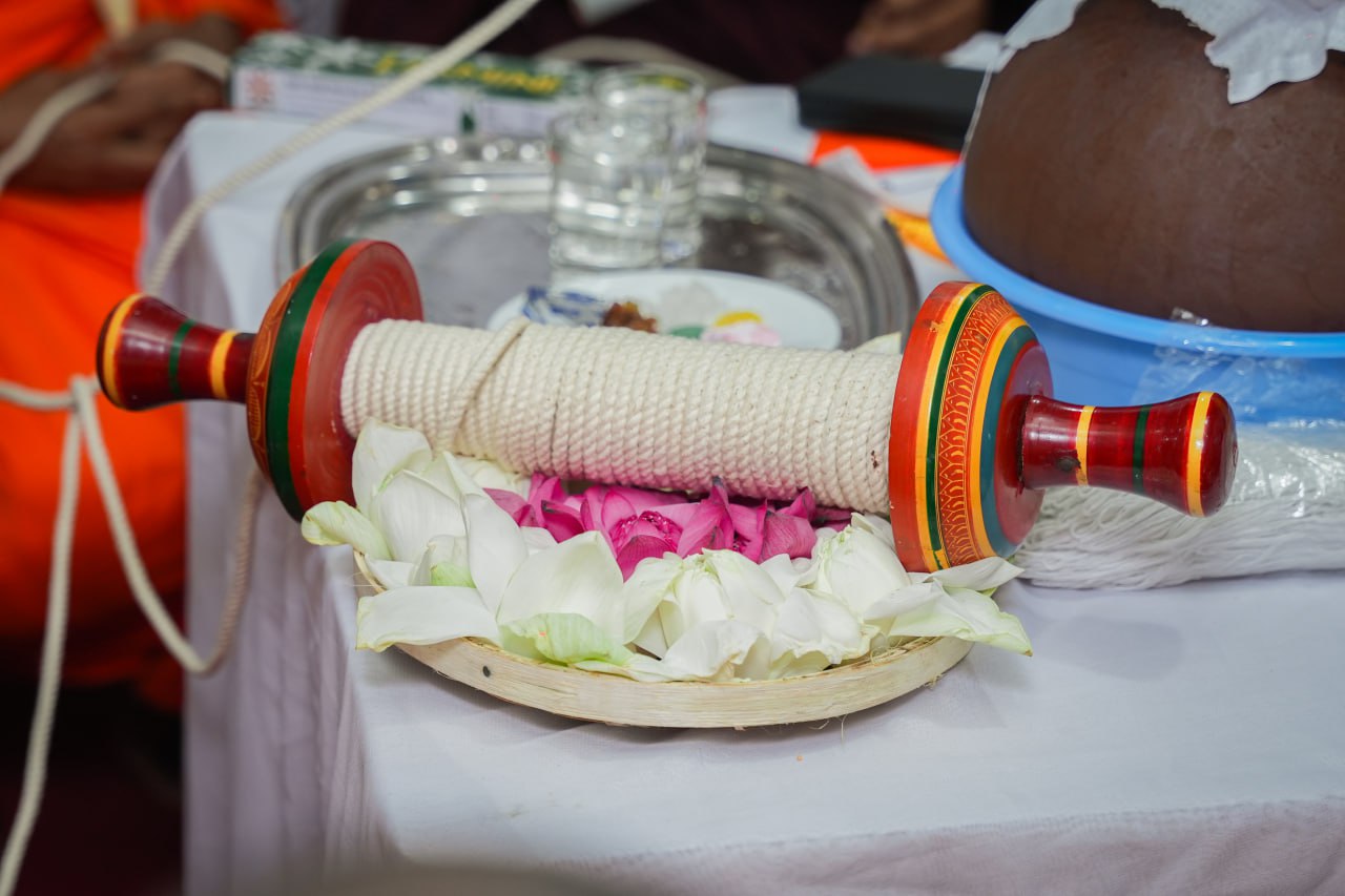 Ceremonial table with decorative spool, flowers, and ritual items.