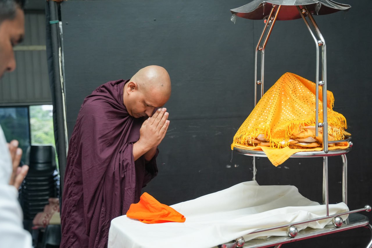 Buddhist monk in prayer beside ornate altar during ceremony.