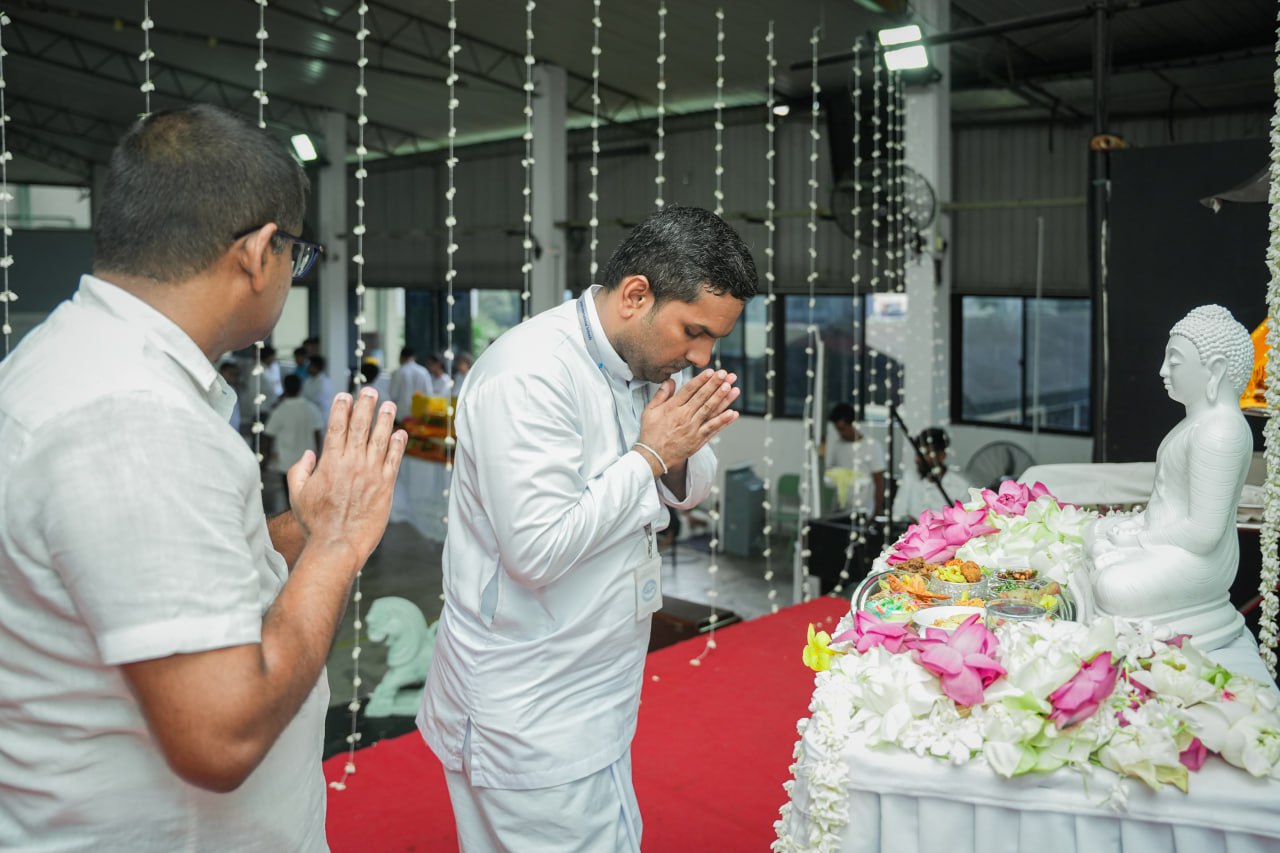 Buddhist ceremony with men in white making offerings to Buddha statue.