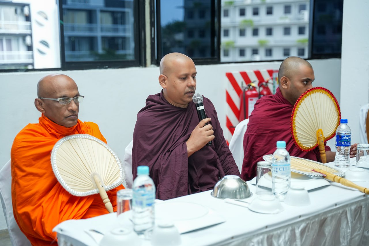 Buddhist monks in traditional robes at an urban ceremony table.
