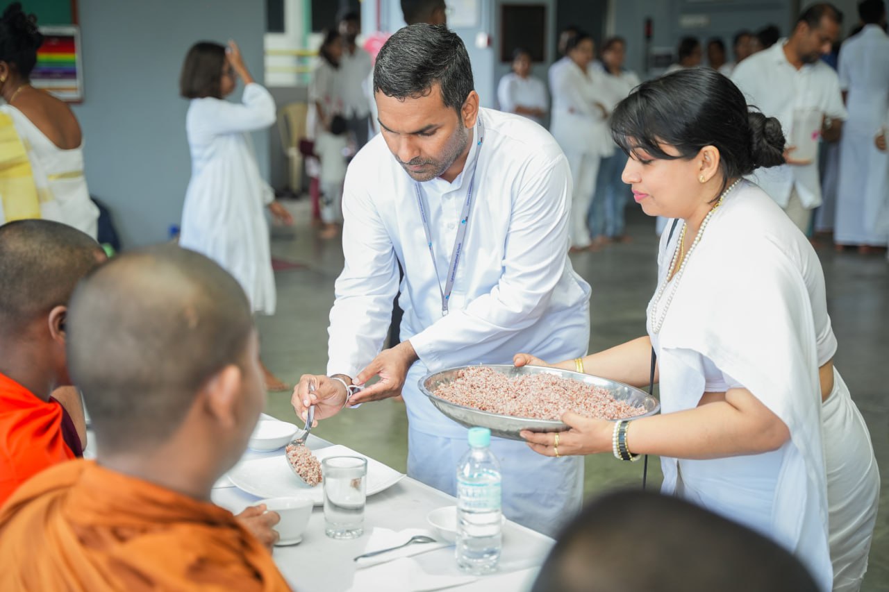 Ceremonial meal service with monks receiving food in a communal religious gathering.