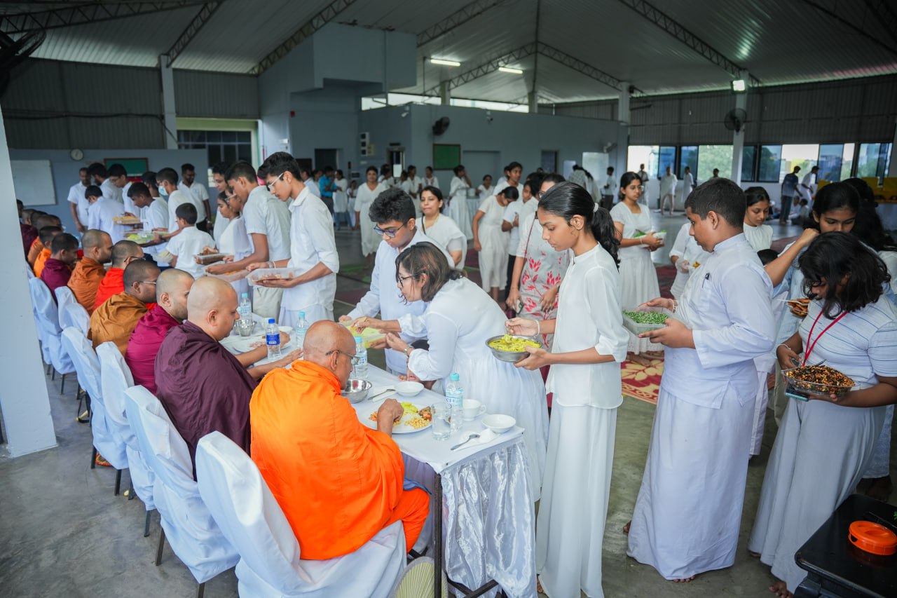 Monks receiving meals from young servers in a serene, well-lit hall.