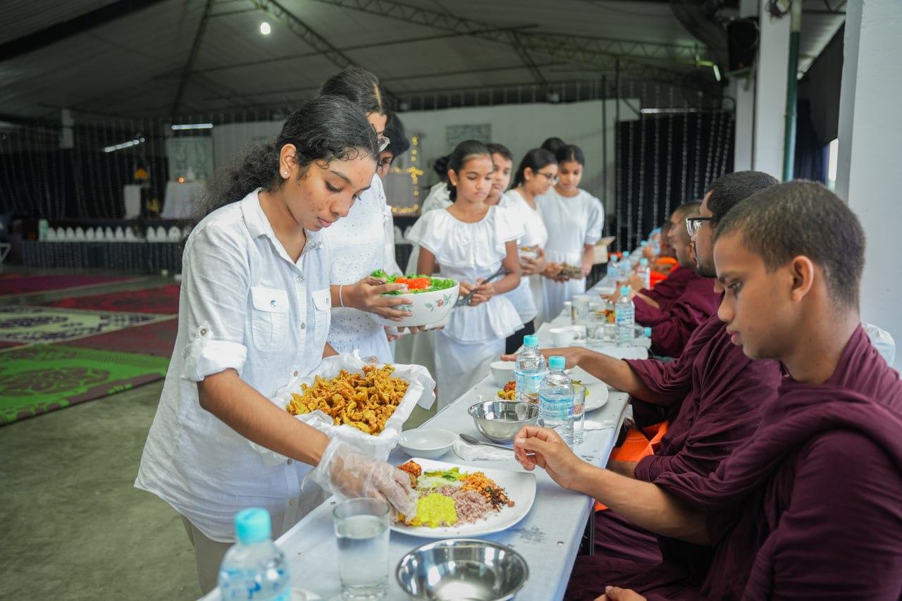 Monastic communal meal with young women serving food to monks.