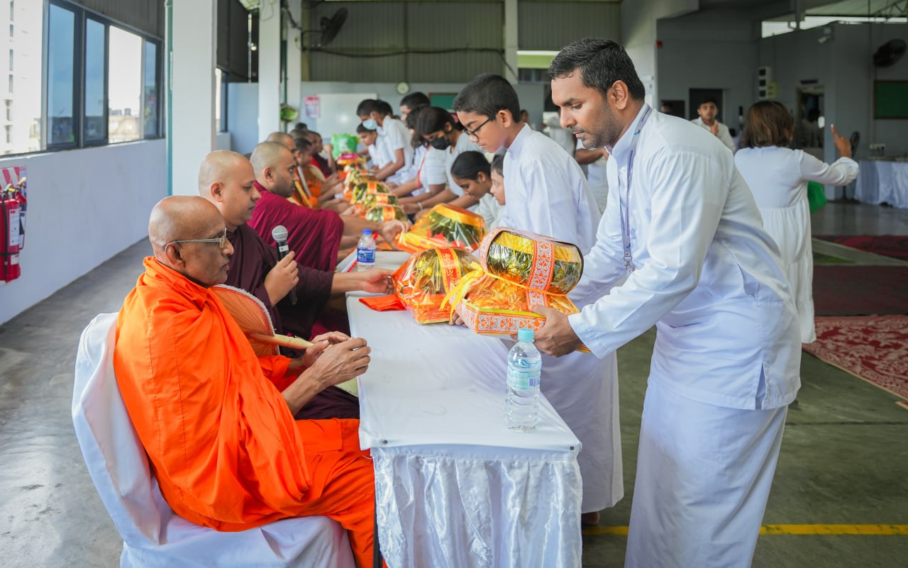 Monks receiving ceremonial offerings with reverence and participation from people dressed in white.