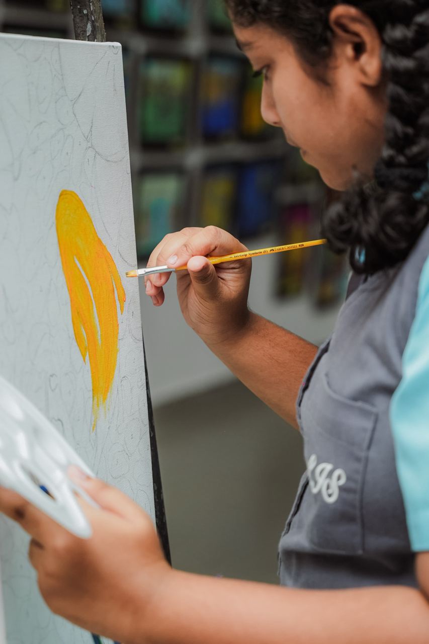 Young Artist Creating with Yellow Paintbrush in Studio Young artist painting with yellow paintbrush in art studio.