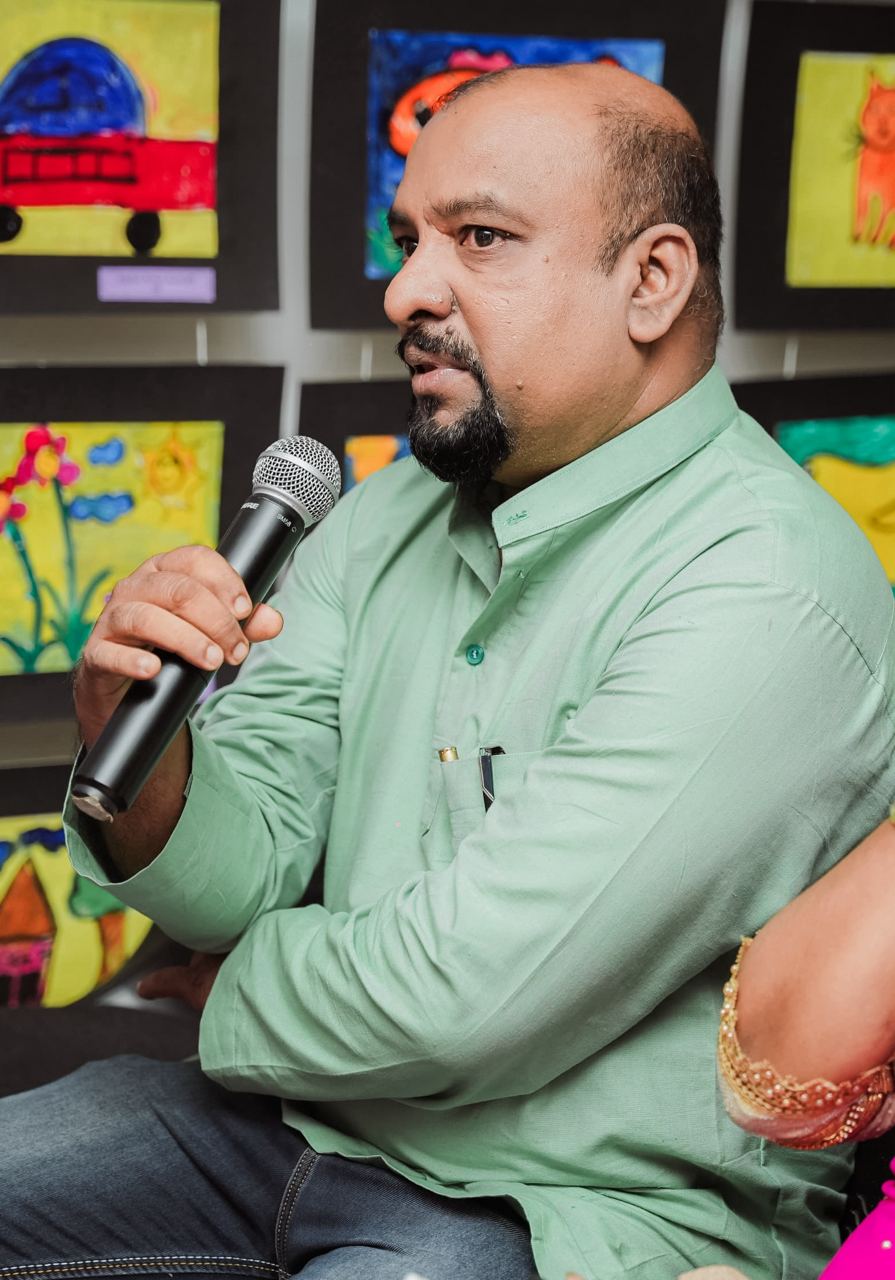 Man Speaking at Colorful Community Art Gathering Man speaking into microphone at colorful community art event.