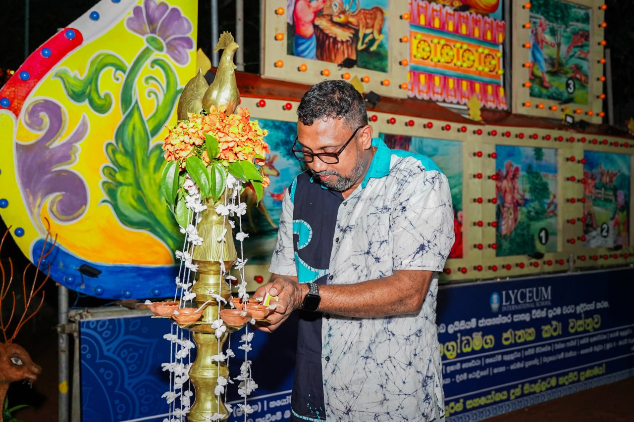 Ceremonial Oil Lamp Lighting at Cultural Festivity Man lighting a brass oil lamp at a vibrant cultural celebration.