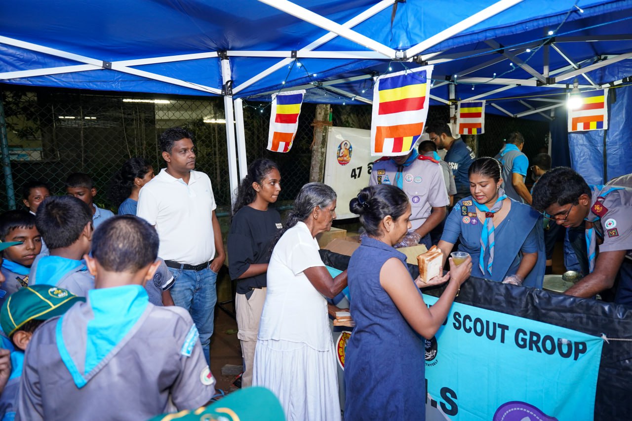 Community Scouts Serving Under Festive Tents Scouts distributing food at a festive community event under illuminated tents.
