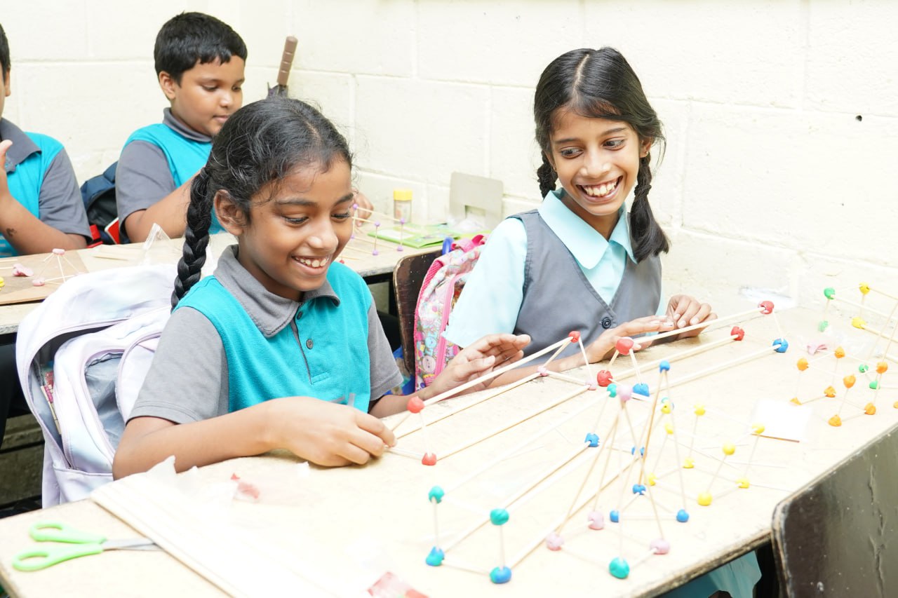 Joyful Geometry Building in the Classroom Children building geometric shapes with sticks and clay in a joyful classroom setting.